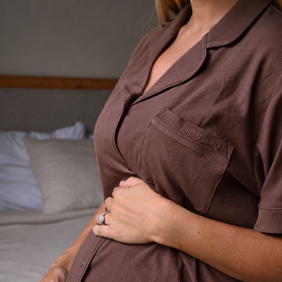 Side view of a mum-to-be in the chocolate maternity pyjama top, hand cradling her growing bump